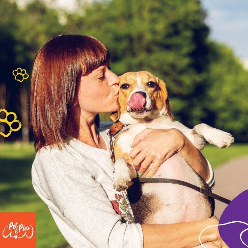 Mujer cargando su perro y besándolo para celebrar el día mundial del perro adoptado.